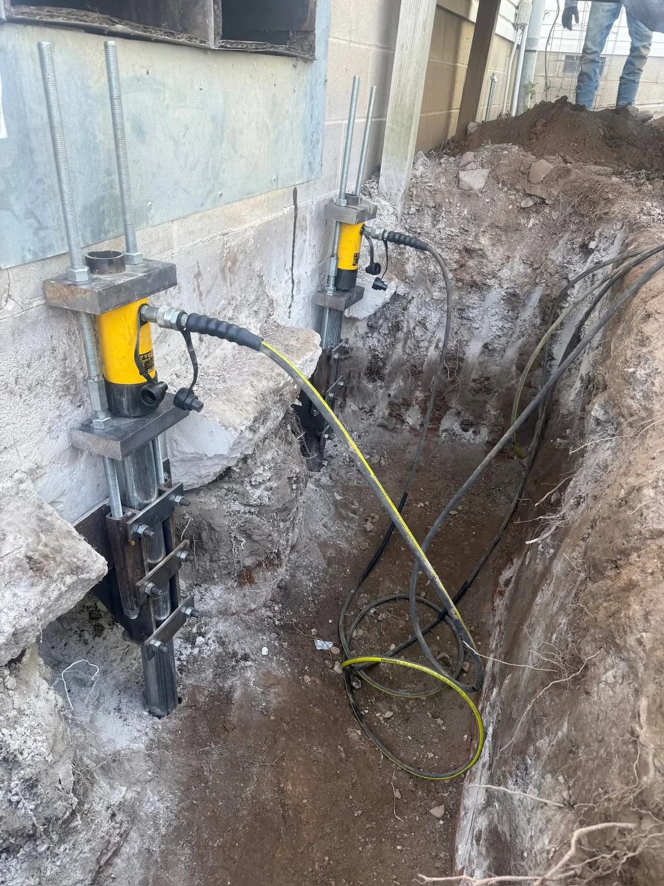 Pier bracket and hydraulic jack installed against a residential foundation